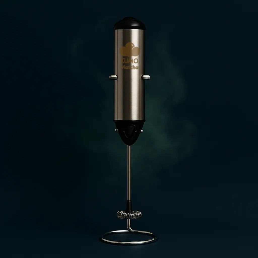 Stainless steel milk frother with black top on a dark background