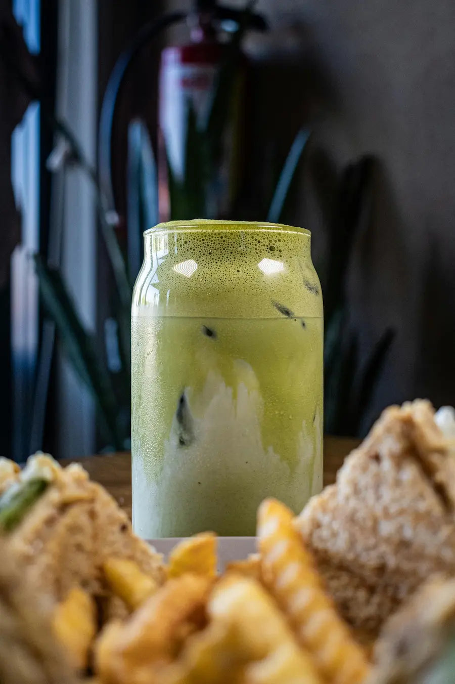 Green smoothie in a jar with snacks on a table